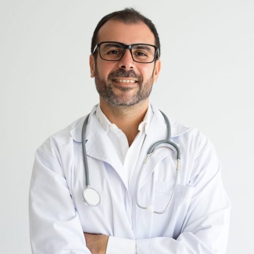 Portrait of successful mid adult doctor with crossed arms. Caucasian general practitioner wearing lab coat, glasses and stethoscope looking at camera and smiling. Medical worker concept
